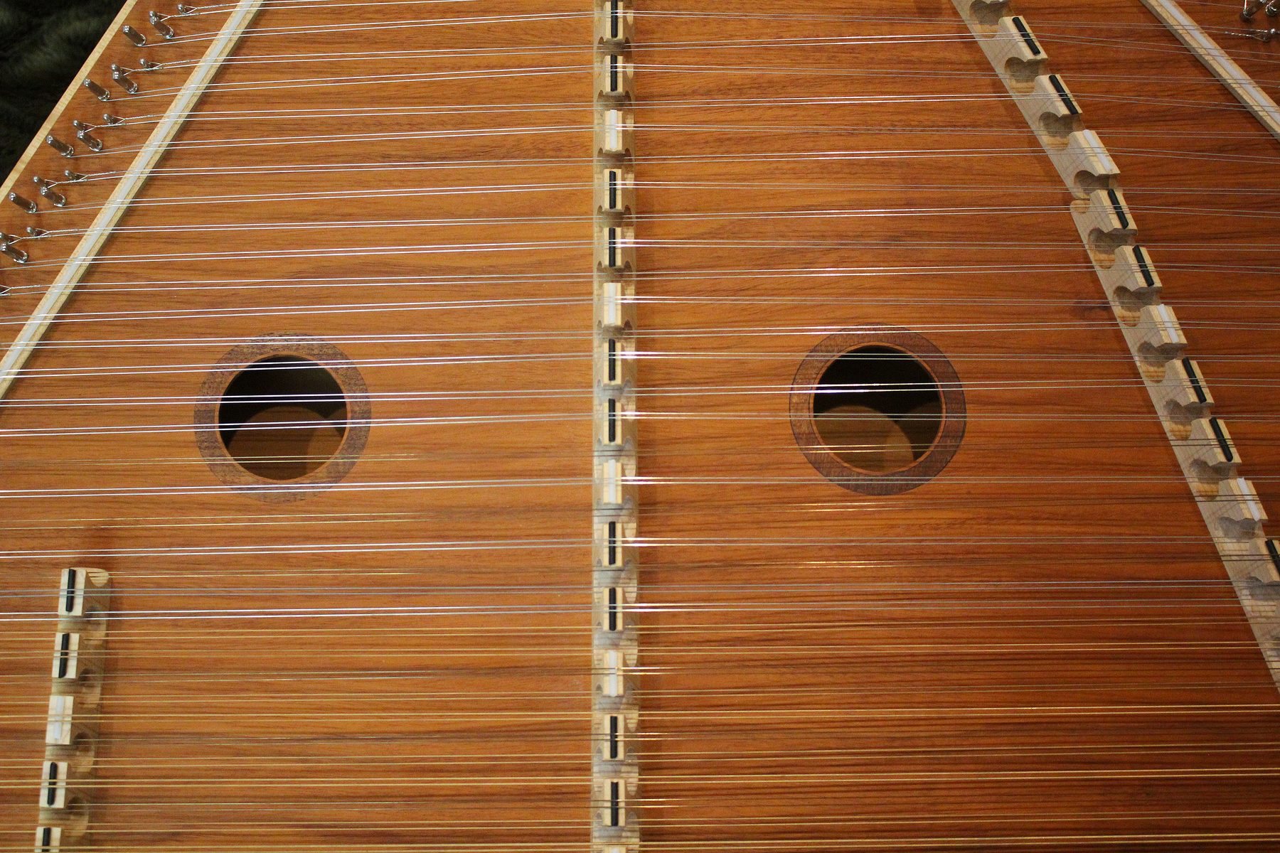 The hammered dulcimer seen from above, bridges and 204 string courses across the mahogany soundboard