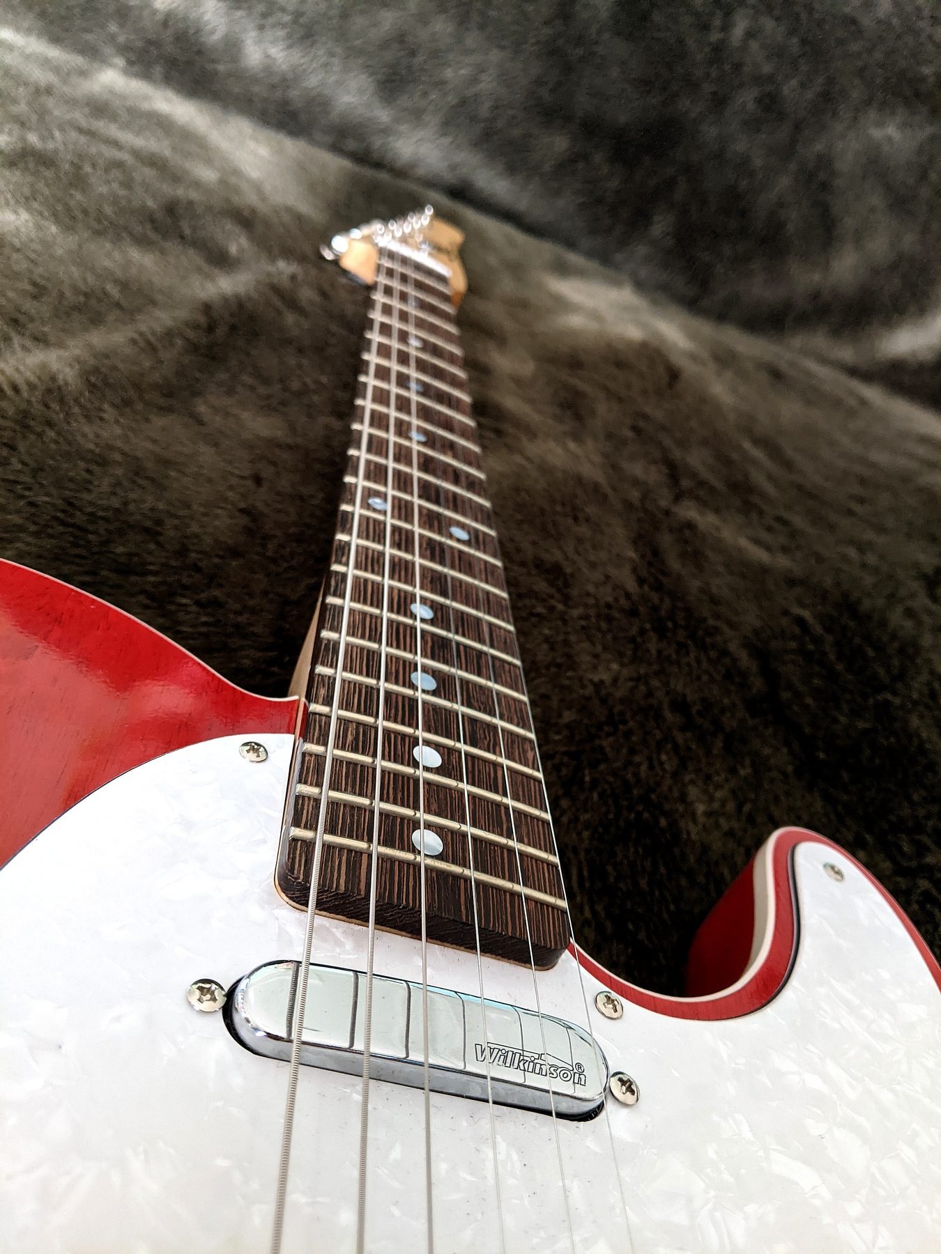 Low front angle across the bridge and control plate of the red Telecaster